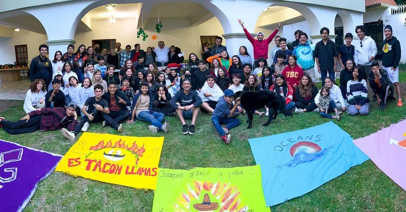 Foto de grupo de los jóvenes de REBORN 2022 en el jardín, con las banderas de los equipos
