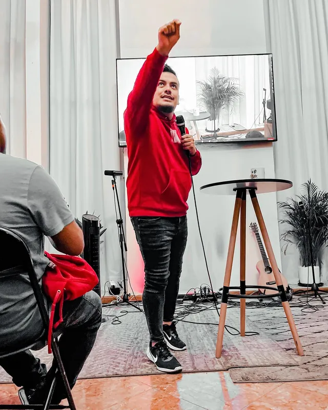 Predicador con sudadera roja levanta el puño mientras predica