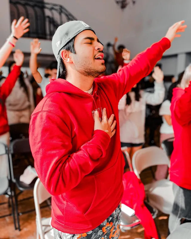Joven con sudadera roja alaba con el brazo levantado