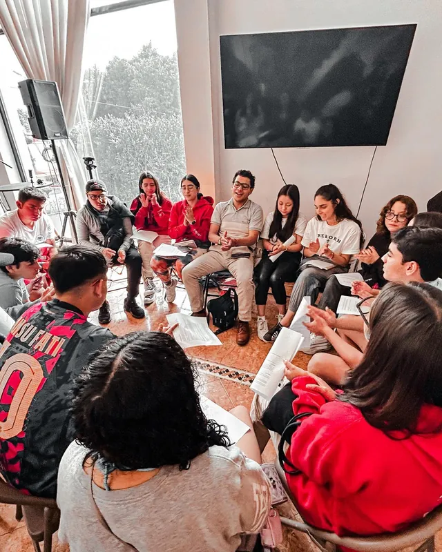 Jóvenes sentados en círculo trabajan en grupo con hojas