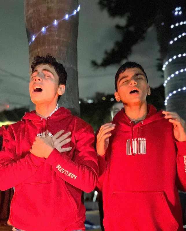 Dos jóvenes alaban de noche con los ojos cerrados