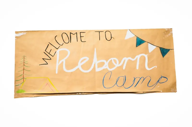 Letrero hecho a mano que dice Welcome to Reborn Camp