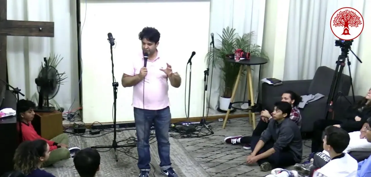 Un pastor predica de pie mientras jóvenes lo escuchan sentados en el piso, en el tercer día de REBORN Camp 2024.