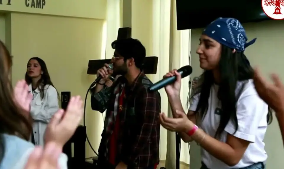 Dos jóvenes cantan y los demás aplauden en el cierre de REBORN 2025.