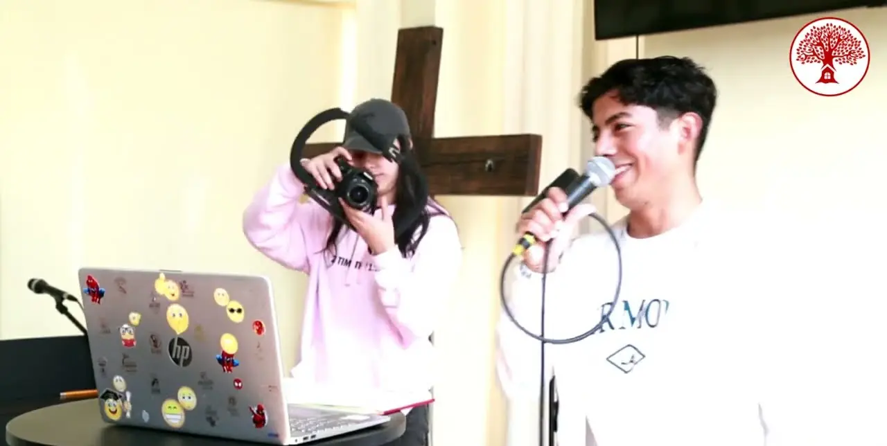 Una joven toma fotos mientras un joven habla con el micrófono en REBORN 2025.