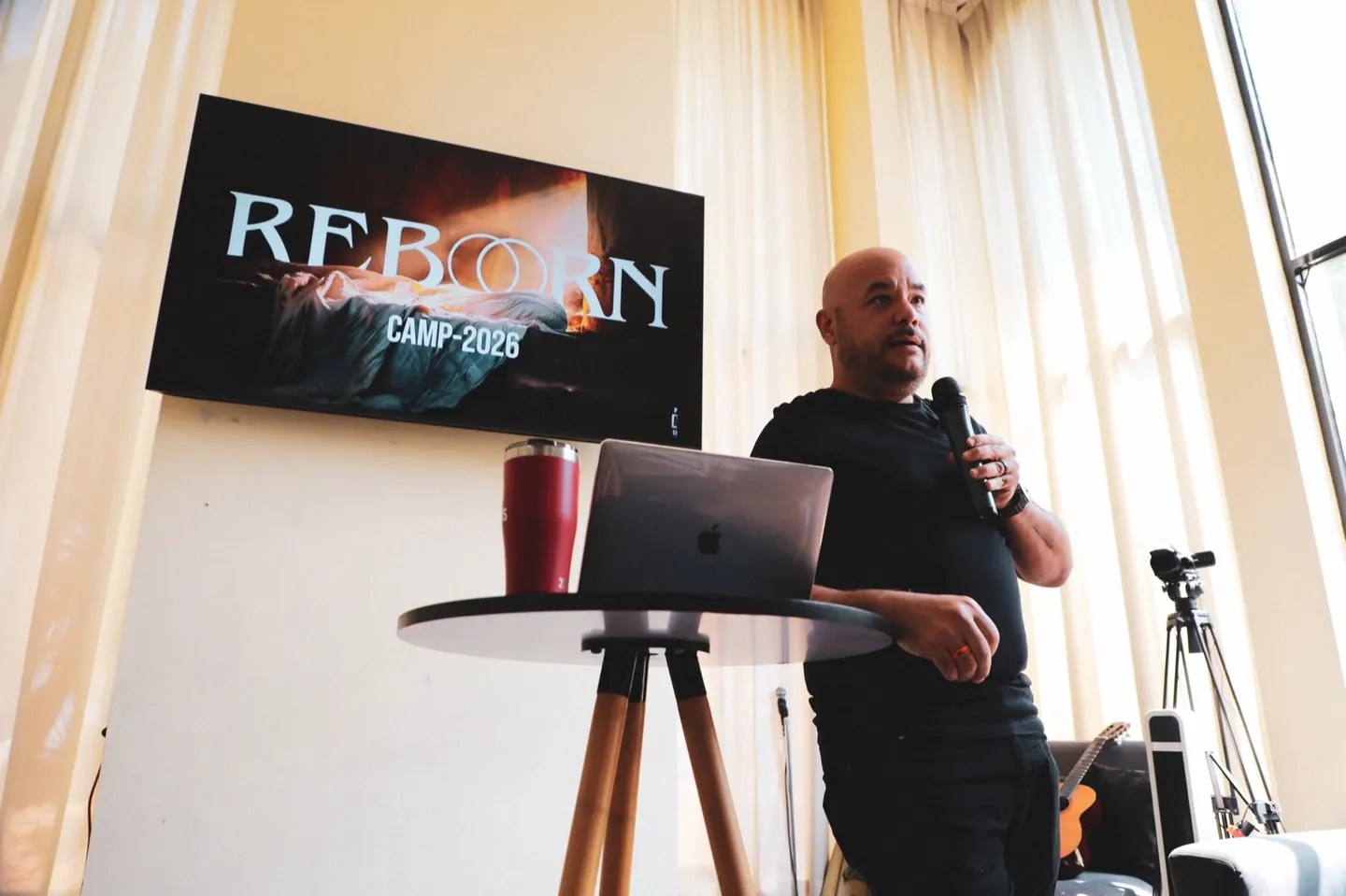 Predicación en REBORN 2026, frente a la pantalla «REBORN CAMP-2026».