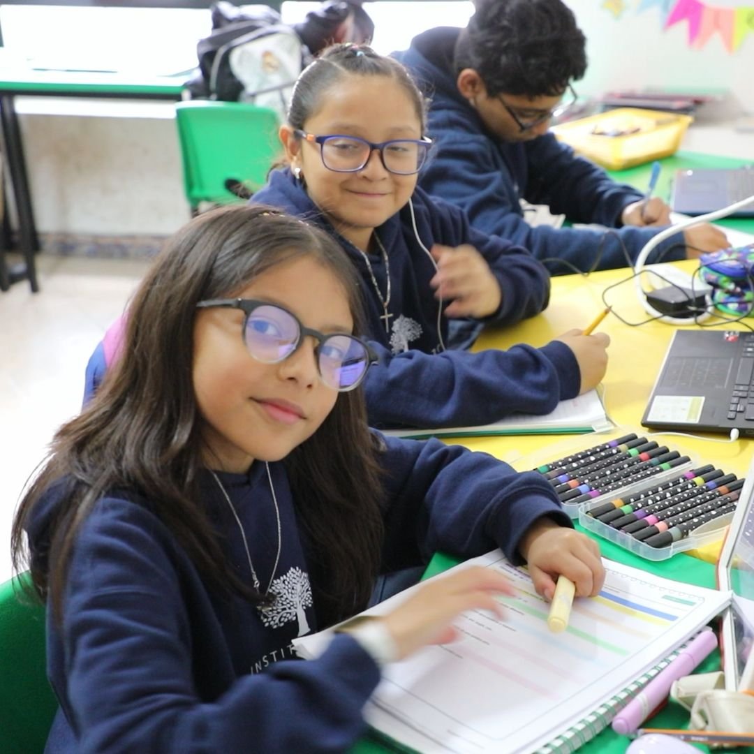 Dos alumnas de Primaria del Instituto Zoe sonríen desde su mesa de trabajo