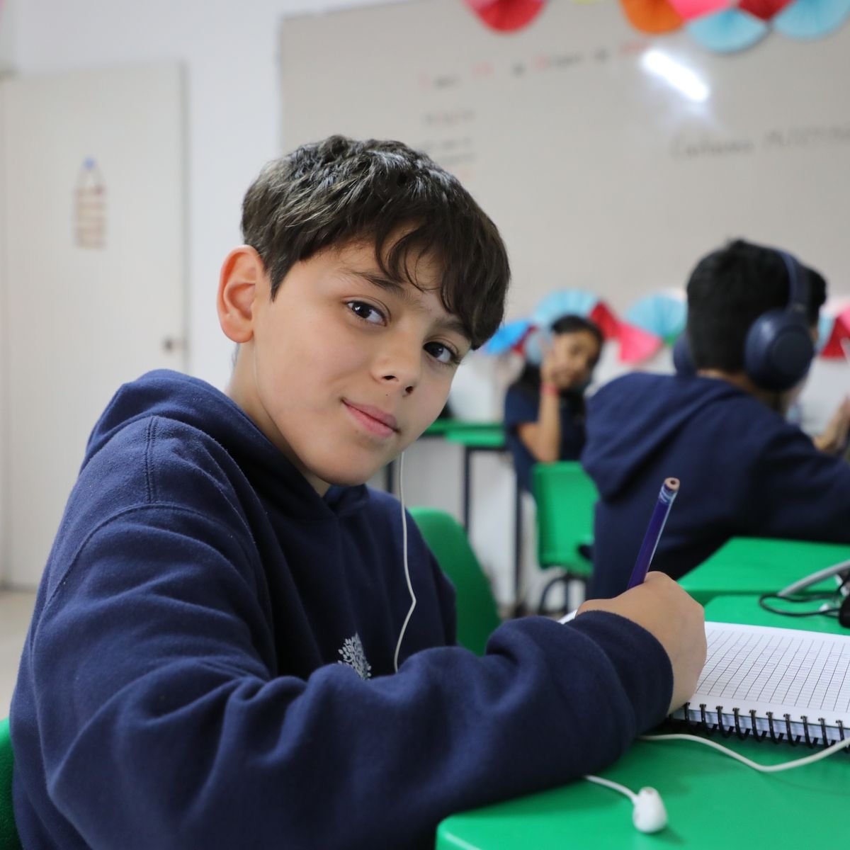 Alumno de Primaria del Instituto Zoe sonríe mientras escribe en su cuaderno