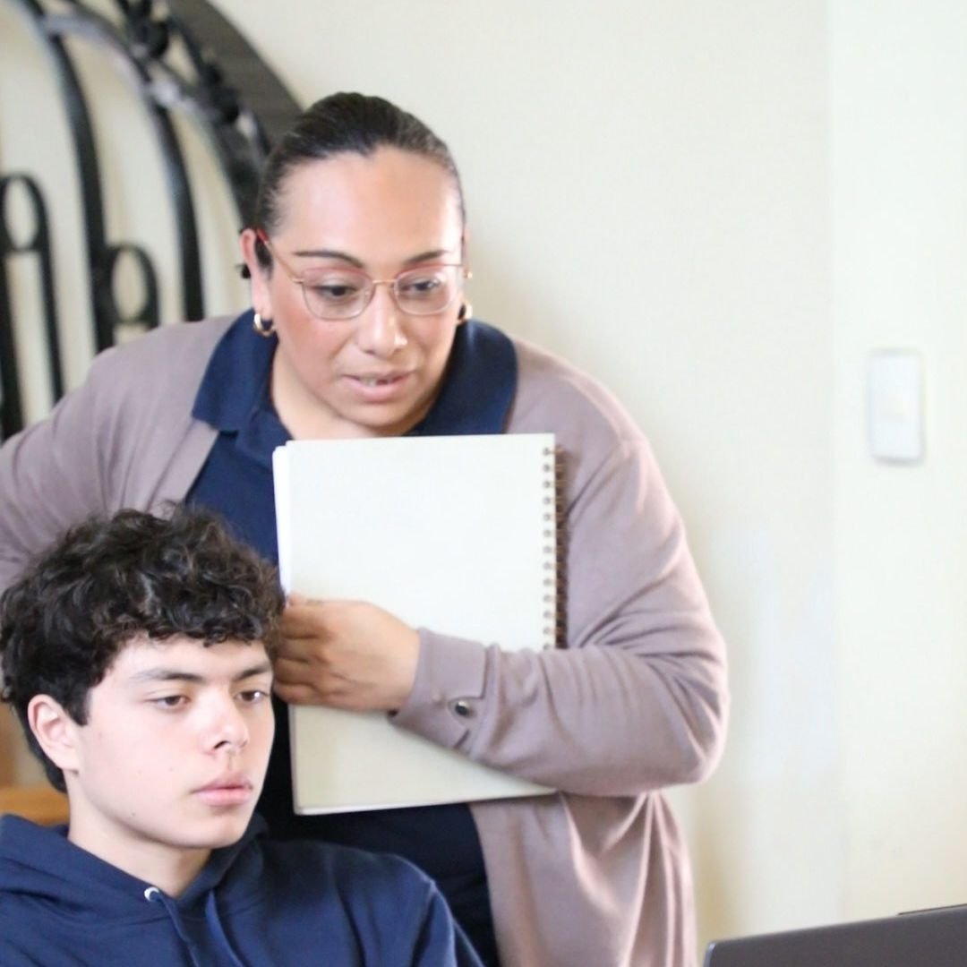 Maestra del Instituto Zoe acompaña a un alumno de Preparatoria en su trabajo