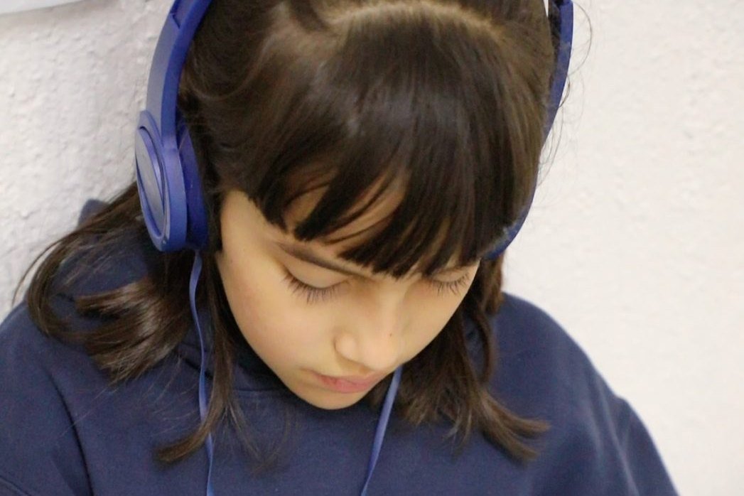 Una alumna del Instituto Zoe, con audífonos, trabaja concentrada en su hoja