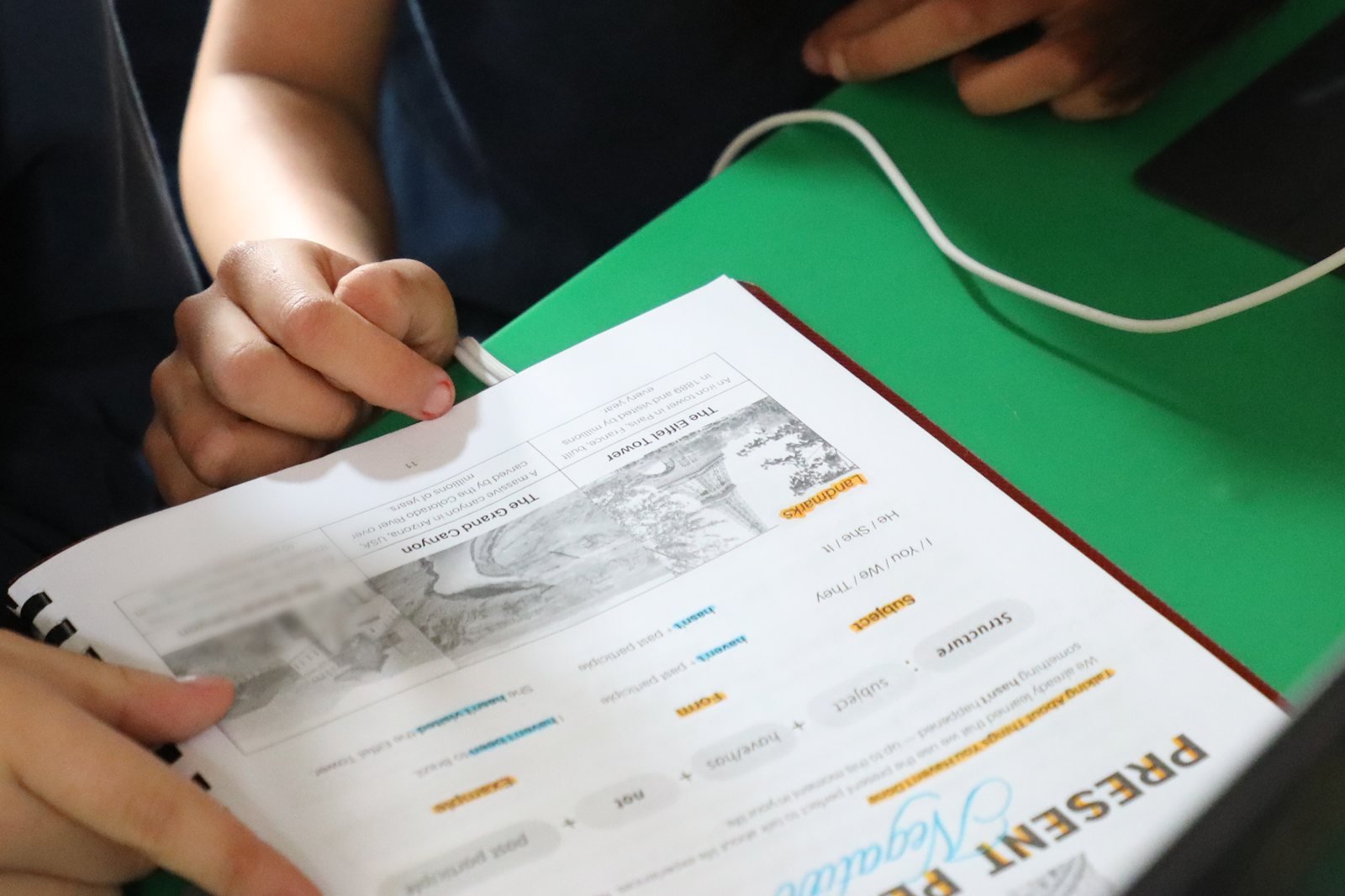 Las manos de una alumna del Instituto Zoe siguen la lección de su libro de inglés, abierto sobre la mesa verde del salón