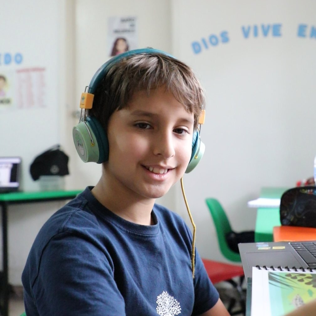 Un alumno de primaria del Instituto Zoe sonríe en su salón, bajo el letrero «Dios vive en mí»