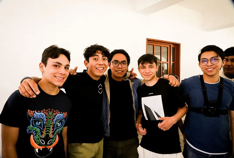 Cinco jóvenes sonríen abrazados