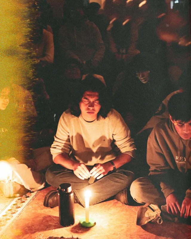 Joven en oración frente a una vela